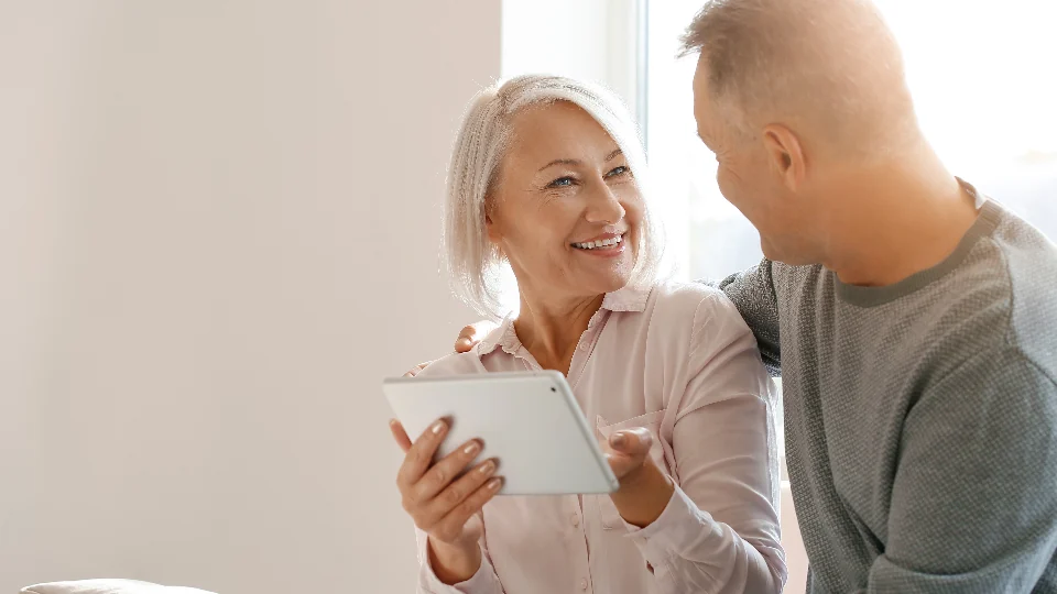 Alexa for Seniors: 9 Easy Setup Steps for Families Older couple at home looking at a tablet together while setting up Alexa for seniors