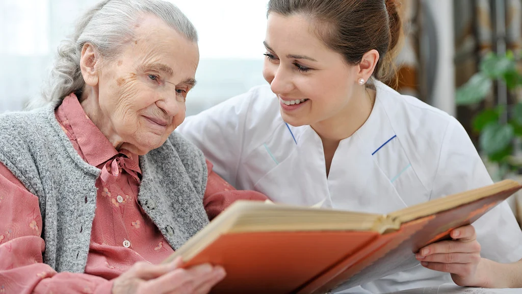 An older woman and a younger woman looking at a book together at home