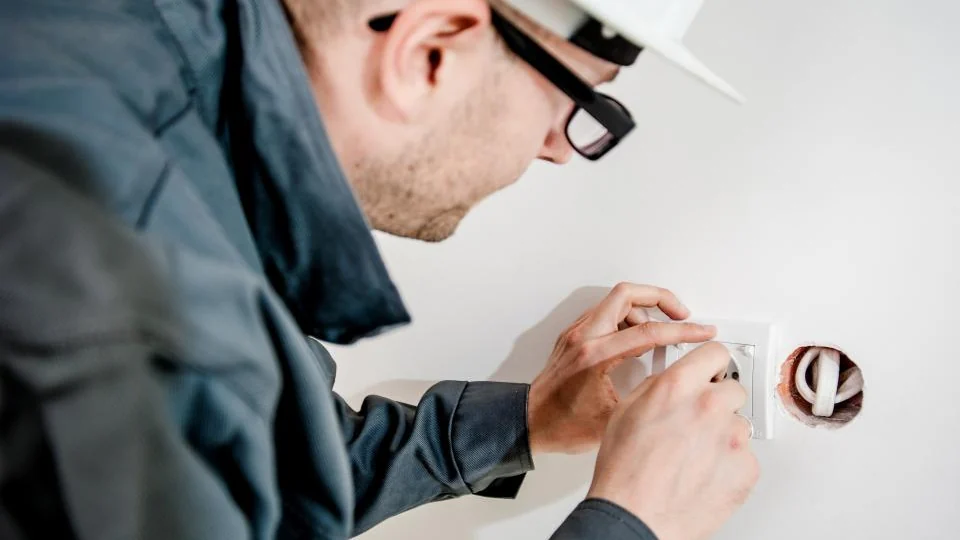 Electrician working on a wall outlet, worth checking before adding a smart plug
