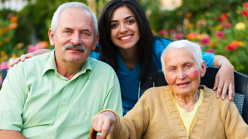 Family members standing with two older relatives outside a house