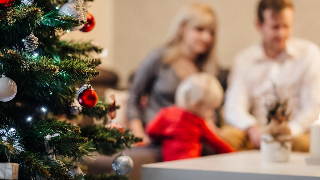 Family sitting together beside a decorated Christmas tree