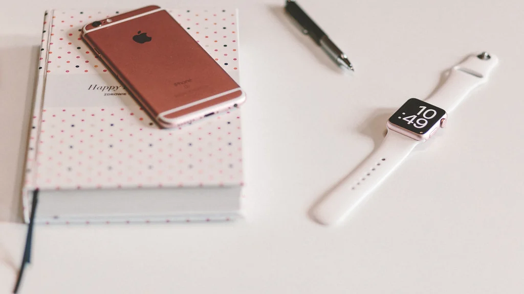 Notebook, pen and smart watch arranged on a desk