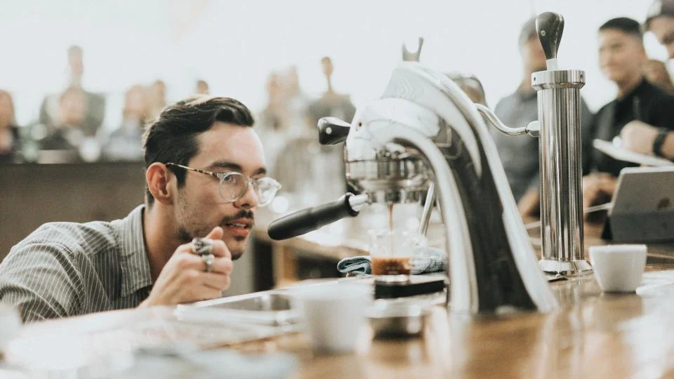 People at a counter with coffee cups and a brewing machine