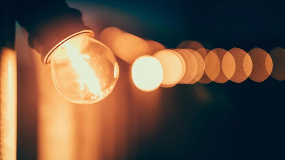 Single light bulb glowing against a dark background